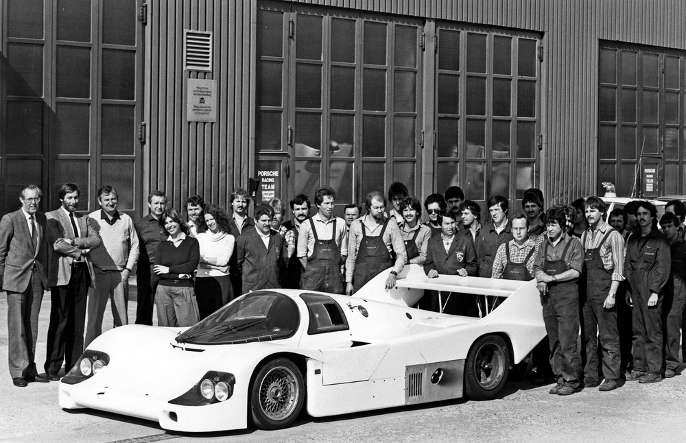 The first 956 for a customer in the racing department in Weissach in 1983. From left to right Peter Falk, Jürgen Barth, Norbert Singer, Julius Weber, 9th from left Fritz Spingler, 13th from left Valentin Schäffer, Hans Eckert, with his hands on the spoiler Günter Gutekunst, 2nd from left of him Herbert Spier, right at the spoiler Rolf Huber. The-first-956-for-a-customer-in-the-racing-department-in-Weissach-in-1983